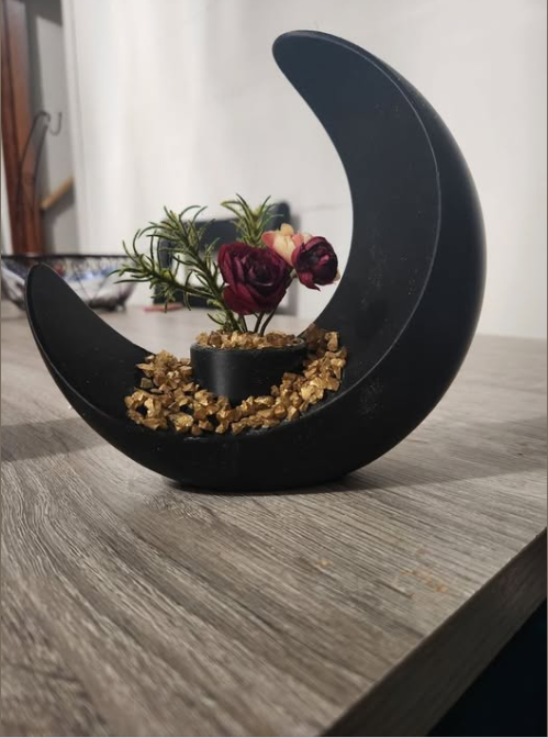 Black crescent moon planter with red flowers and gold stones